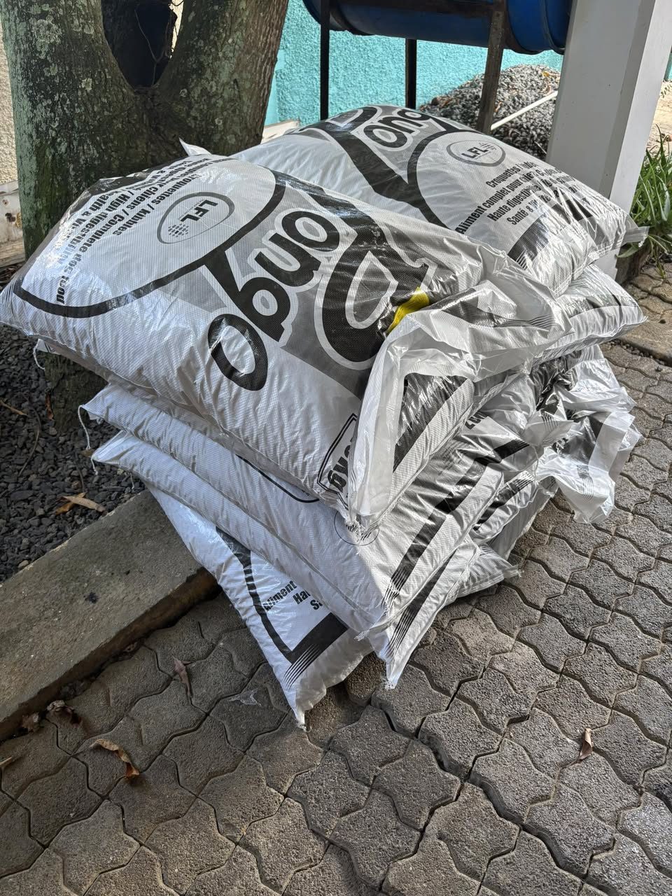 Stacked bags of animal feed supplies piled on a paved outdoor walkway