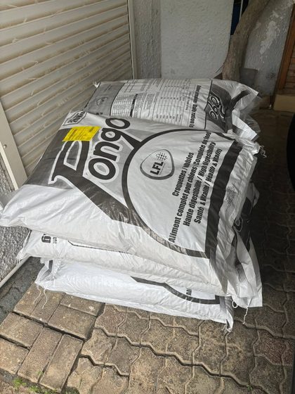 Stacked bags of Pongo dog kibble on a paved outdoor floor