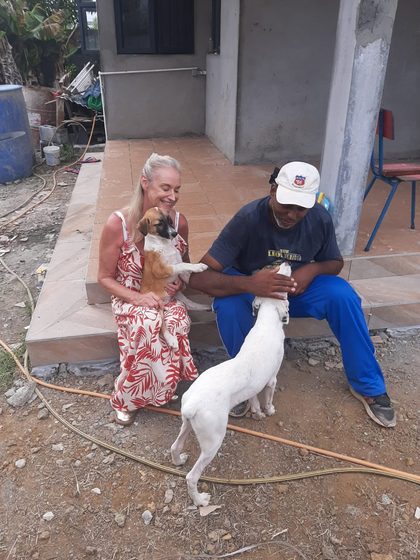 Two dogs with a woman and man sitting on concrete steps outside a building